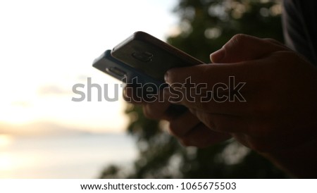 A man is holding two phones in his hands at sunset. hd