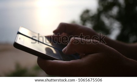 A man holding two phones in his hands on the screens reflects the sunset. hd