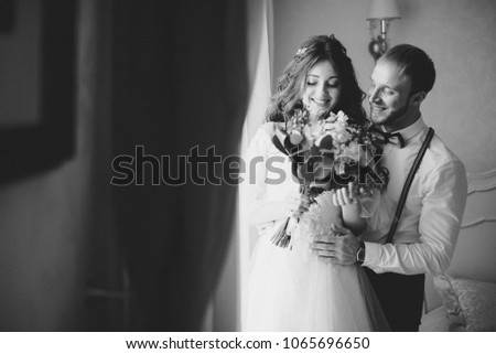 stylish groom with beard and beautiful bride posing in hotel