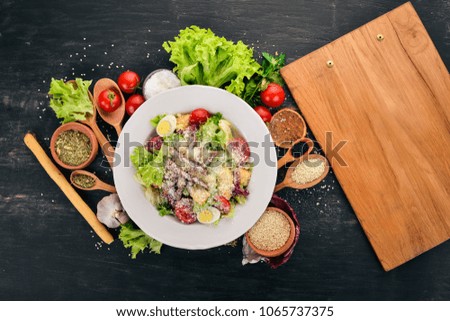 Caesar salad with beef. On a black wooden background. Top view. Copy space for your text.