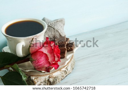 A cup of coffee, pieces of chocolate and a pink rose. Romantic breakfast.