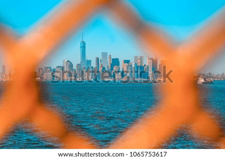 New York skyline through the orange barrier grid of the Staten Island ferry