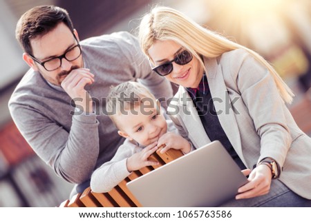 Happy family having fun outdoors with a laptop.