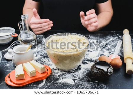 Pizza dough, pie or pasta on a dark table and men's hands work with flour and dough