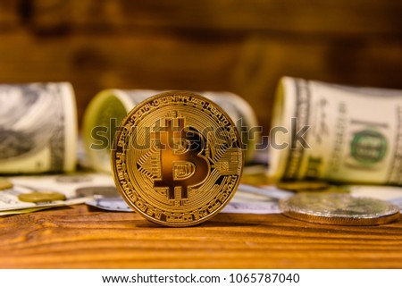 Bitcoins and one hundred dollar bills on rustic wooden table