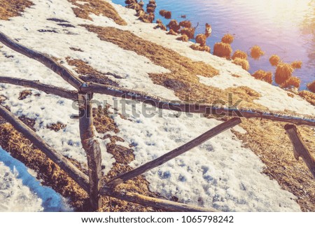 wooden fence on the shore of a pond