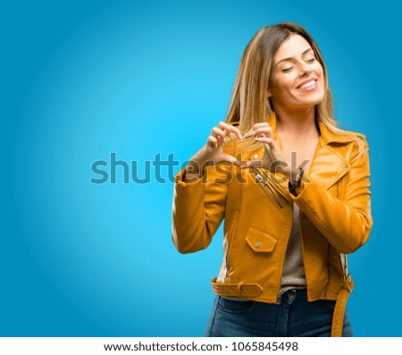 Beautiful young woman happy showing love with hands in heart shape expressing healthy and marriage symbol, blue background