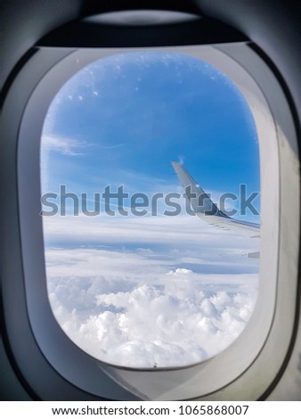 Image of airplane wing, cloudy sky from porthole