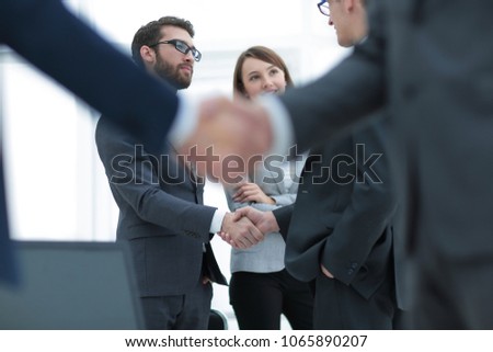 Two businessmen shaking hands with colleagues  on background.