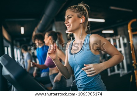 Young people running on a treadmill in health club. Royalty-Free Stock Photo #1065905174