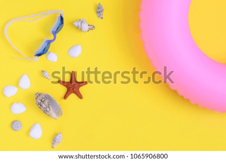 Shells, starfish and glasses for swimming on a yellow background. A big inflatable pink circle in the corner. Beautiful summer picture.