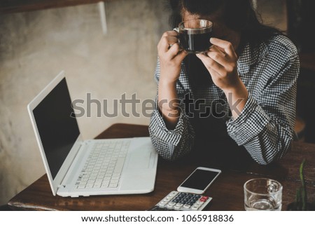 Feeling tired and stressed young woman of working age is working on a wooden table in coffee shop