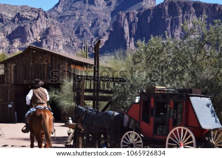 Cowboy on horseback with stage coach and old barn near the Superstition Mountains in arizona