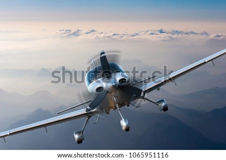 Privat light airplane or aircraft fly on mountain background. VIP travel concept Royalty-Free Stock Photo #1065951116