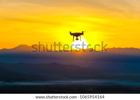 Hobby recreation with Drone quadcopter flying on mountain sunset silhouette scene nature landscape
