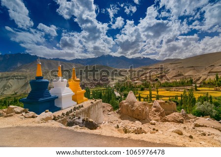 Three colourful buddhist religious stupas at Basgo, Leh, Ladakh, Jammu and Kashmir, India. Blue sky with clouds and Himalayan mountains in the background.