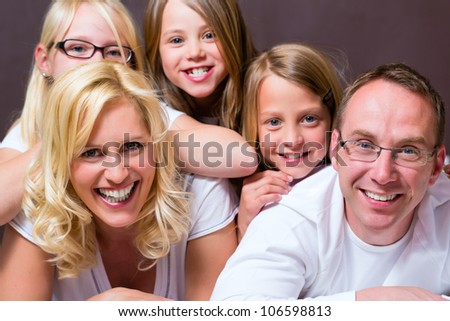 Group picture of a young family, father, mother and three children in bedroom