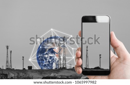 Hand holding mobile smartphone, and telecommunication towers with wifi signal signs and global network connection. Element of this image are furnished by NASA