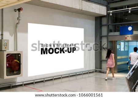 Mock up blank billboard on the wall in the corridor to elevator, Empty white banner for public information the indoor advertisement, blurred people walk in. Business marketing and advertising concept