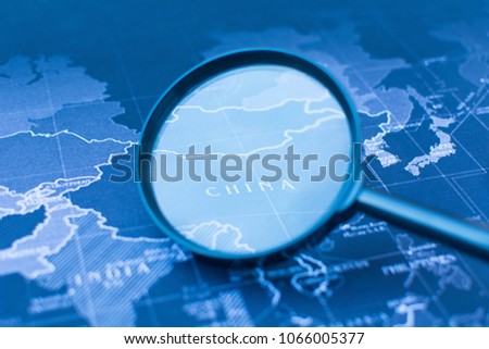 Magnifying glass on the world map selective focus of China, war concept.