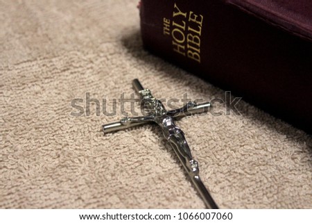 Silver color cross next to Holy bible.