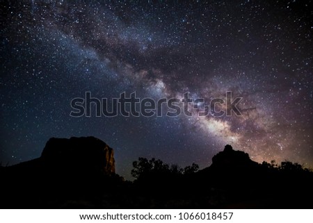 The Milky Way Galaxy arcs across the sky from Bell Rock over Courthouse Butte on a dark night near Sedona, Arizona.