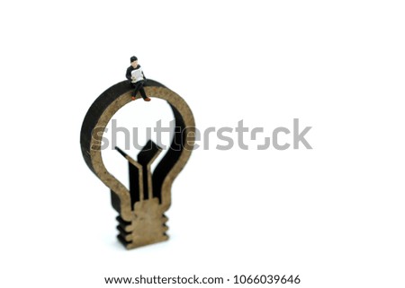 Miniature people : Businessman reading newspaper on wooden lamp idea,Business vision concept.