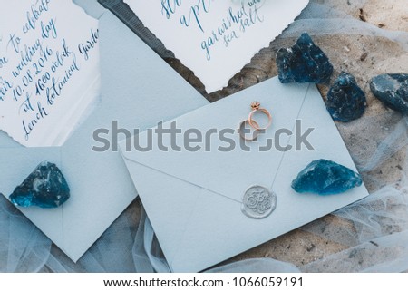 Wedding and engagement rings on an envelope next to invitation and menu