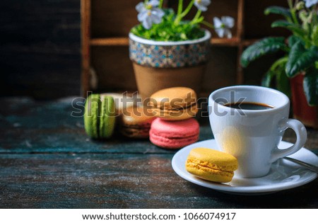 Beautiful breakfast. Morning cup of coffee with colorful macarons, on with flowers on dark background with copy space. Selective focus