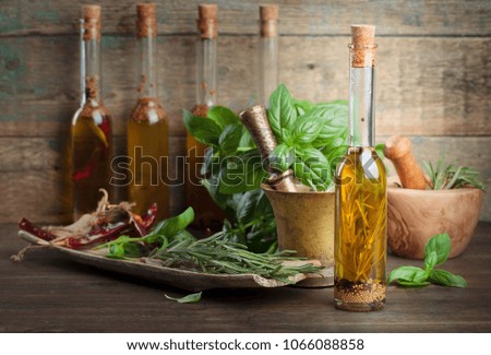 Olive oil with different spices and herbs on a old wooden table.