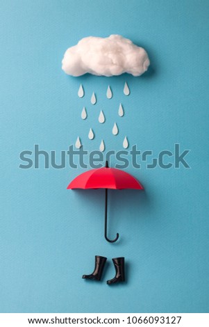 umbrella and rain boots under the cloud on sky blue background