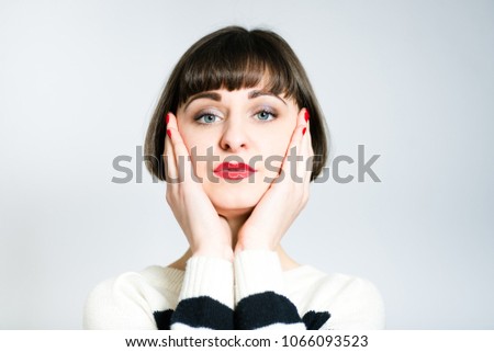 beautiful girl touches her healthy skin, short haircut, studio photo on the background
