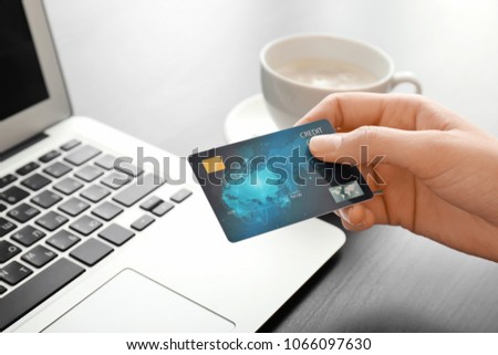 Young woman with credit card using laptop at table