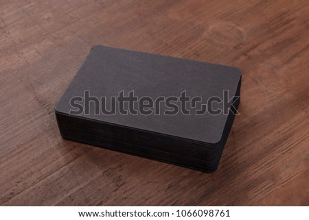 A mockup for a stack of black business cards with rounded edges on a rustic background, with a place for text