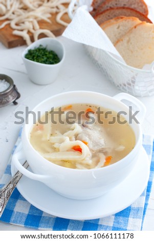 Hot homemade soup on chicken broth with homemade noodles in a white cup, selective focus