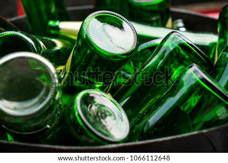 Pile of empty beer, green glass bottles, invert bottom up collected in steel bin for recycle selling. Container industry or waste management concept. Royalty-Free Stock Photo #1066112648
