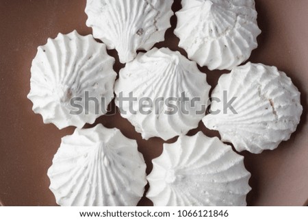Sweet dessert white zephyr marshmallows on clay plate and rustic wooden background