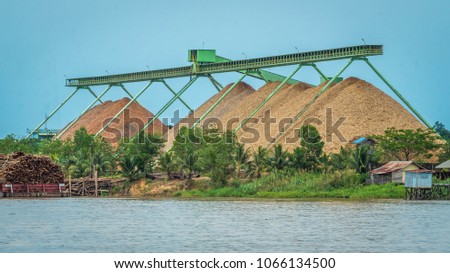 wood chip factory on Mahakam riverbank with conveyor and stockpile. Indonesia