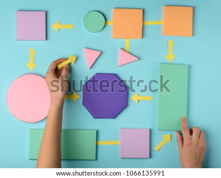 Woman making a flow chart. Color paper 3D blocks connected with arrows. Solution of a problem.