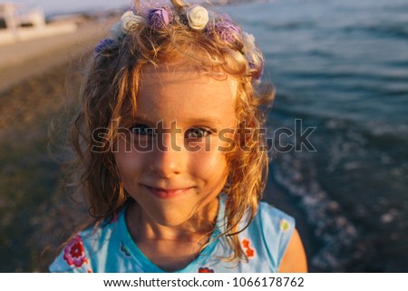 close up portrait of a cute smiling child girl in blue dreass and flower wreath