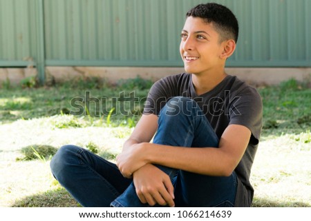Teenage boy sitting in the garden.
Outdoor portrait of a smiling teenage boy, blurred green fence in background.
 Royalty-Free Stock Photo #1066214639