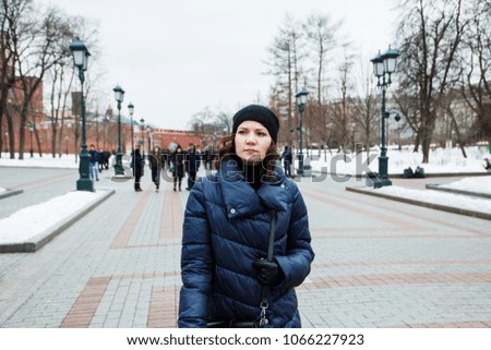 portrait of a girl in a coat on the street in the city on the background of people.