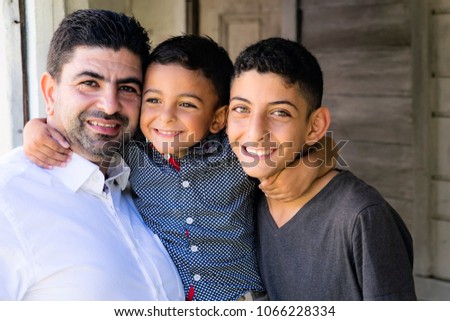 Outdoor portrait of a father and his sons.
Father and older brother smiling and hugging cute little boy.
 Royalty-Free Stock Photo #1066228334
