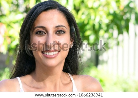 Outdoor portrait of an attractive woman.
Closeup portrait of a smiling brunette woman in garden, blurred green tree background.
 Royalty-Free Stock Photo #1066236941