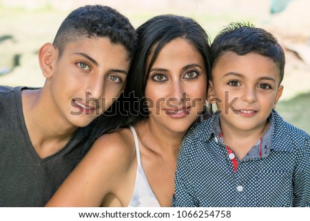 Outdoor portrait of a smiling mother and her sons.
Attractive brunette mother and two brothers smiling in garden.
 Royalty-Free Stock Photo #1066254758