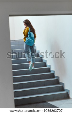 rear view of schoolgirl with backpack walking upstairs Royalty-Free Stock Photo #1066263707
