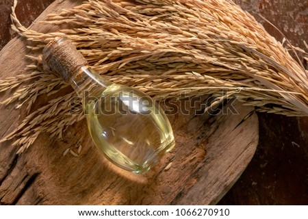 Bottle of rice bran oil and unmilled rice on wooden background. Royalty-Free Stock Photo #1066270910
