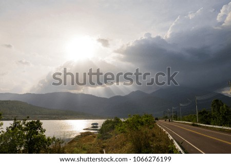 The road of sky and cloud on lagune or lagoon when sunset in the evening of winter with big trees. Silhouettes landscape of meadow and sunset over mountain.