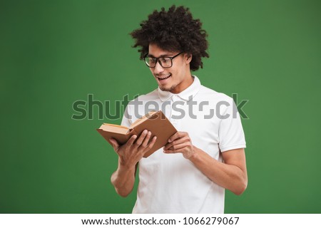 Picture of concentrated young african curly man isolated over green wall background holding book reading.