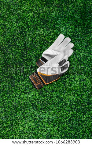 Gloves of the goalkeeper, football player, athlete, white, black, orange on a green lawn. Place for the inscription, rest, break, timeout, fatigue. After the game, used Close-up, top view flatley Royalty-Free Stock Photo #1066283903
